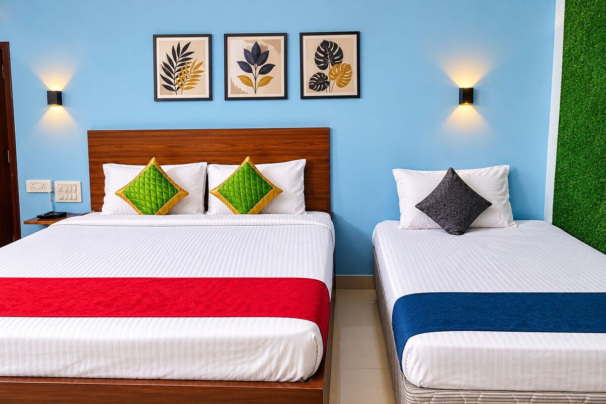 Habitación de hotel con dos camas, cabecero de madera, pared verde y tres obras de arte con hojas enmarcadas.