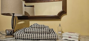 Une salle de bain avec un miroir, une horloge, une serviette à motifs, un flacon de parfum et une assiette décorative.