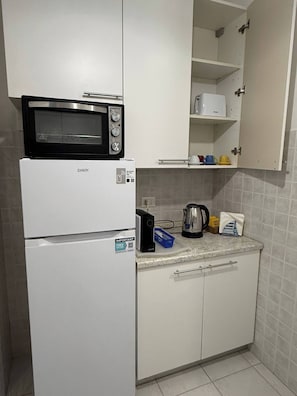 Ett kompakt kök med en mikrovågsugn, ett kylskåp och en kaffebryggare på bänkskivan.