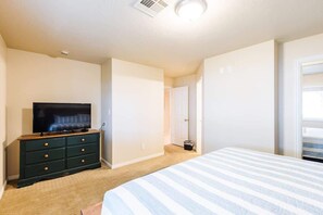 A bedroom with a bed, a dresser, a television, and a door leading to another room. - Las Palmas 1605 | Next to Clubhouse and Pool! (Saint George)