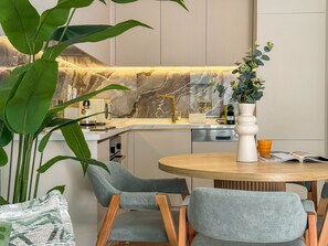 A modern kitchen with a marble backsplash, a round dining table with chairs, and a potted plant. - Qoople Legend 37 А-12 100 Meter vom Strand entfernt by Interhome (Alanya)