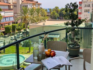 A balcony with a table, chairs, a potted plant, and a view of the cityscape. - Qoople Legend 37 А-30 100 Meter vom Strand entfernt by Interhome (Alanya)