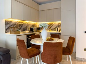 A modern kitchen with a marble backsplash, a white vase with flowers, and a round dining table with brown chairs. - Qoople Legend 37 А-30 100 Meter vom Strand entfernt by Interhome (Alanya)