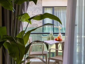 Ein Balkon mit Tisch, Stühlen, einer Blumenvase und einer Flasche.