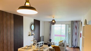 A modern living space with a dining area, a sofa, and a balcony with curtains.