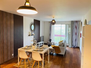 A modern living space with a dining area, a sofa, and a balcony with curtains. - SADAM NEST PRIVATE (Le Mans)