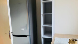 A kitchen with a refrigerator, a white cabinet, a table with a lemon-patterned tablecloth, and a woven basket. - SADAM NEST PRIVATE (Le Mans)