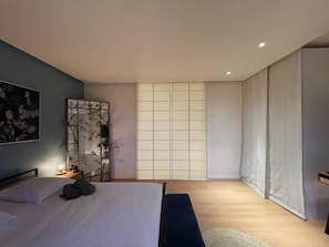 Ein modernes Schlafzimmer mit Bett, Nachttisch und einem großen Fenster mit Blick.