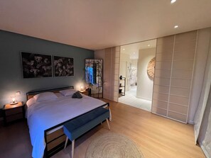 A modern bedroom with a large bed, bedside lamps, and artwork on the wall. - Maison d’architecte lumineuse • Au cœur des Vosges (Deyvillers)