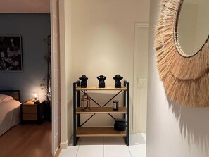 Ein Schlafzimmer mit einem Bett, einem Nachttisch, einer Lampe und einem an der Wand befestigten Spiegel.
