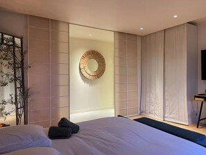 Une chambre moderne avec un grand lit, un miroir fixé au mur et un téléviseur.
