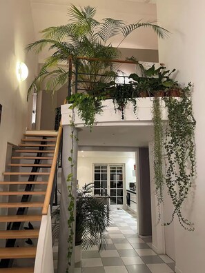 A staircase with wooden steps and a white railing, leading to a landing with a view of a kitchen area. - Maison d’architecte lumineuse • Au cœur des Vosges (Deyvillers)