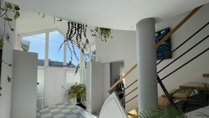 A modern interior with a staircase, checkered floor, and hanging plants. - Maison d’architecte lumineuse • Au cœur des Vosges (Deyvillers)