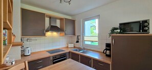 Eine kompakte Küche mit Backofen, Mikrowelle und einem Fenster für natürliches Licht.