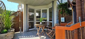 En uteplats med ett träbord och stolar, en krukväxt och ett trästaket.