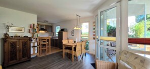 Eine kompakte Küche mit Essbereich, Holzmöbeln und einem großen Fenster mit Blick ins Freie.