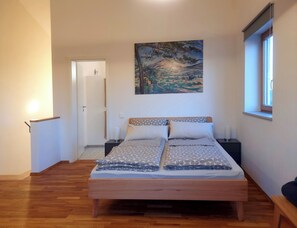 Une chambre à coucher avec un lit, un tableau, une fenêtre et une porte.