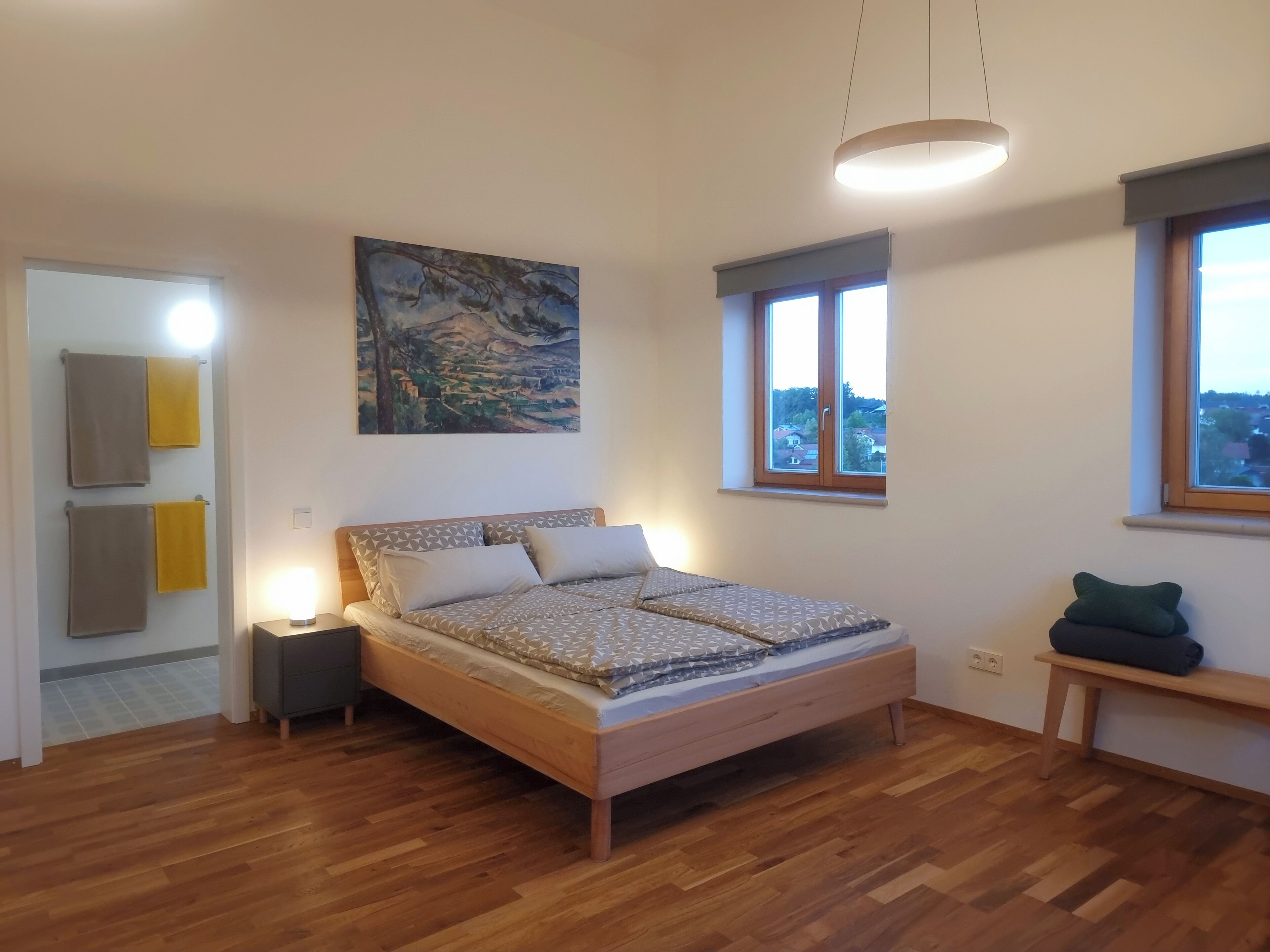 Un dormitorio con cama, mesita de noche y una pintura en la pared.