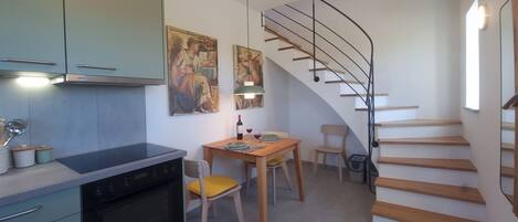 Una cuina moderna amb zona de menjador, una escala i obres d'art a les parets.