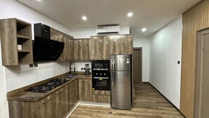 Een moderne keuken met houten kastjes, een roestvrijstalen koelkast en een inbouwoven.
