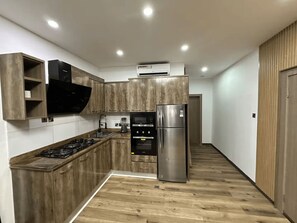 A modern kitchen with wooden cabinets, a stainless steel refrigerator, and a built-in oven. - Modern 1-Bedroom Apartment in Lekki 1 with Fast Wi-Fi & 24/7 Power (Lekki)