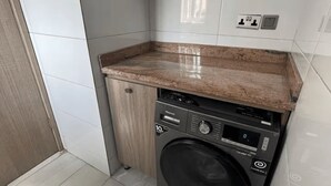 Een kleine wasruimte met een wasmachine, een aanrecht en een kast.