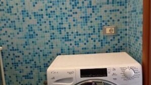 A compact laundry room with a washing machine, a tiled wall, and a metal shelf unit. - Spacious 2-bedroom, 2-bathroom apartment near the Colosseum in Rome (Roma)