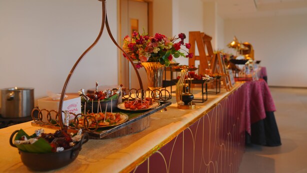 A buffet setup with various dishes and a floral centerpiece. - Travancore Palace, Cochin (Aluva)