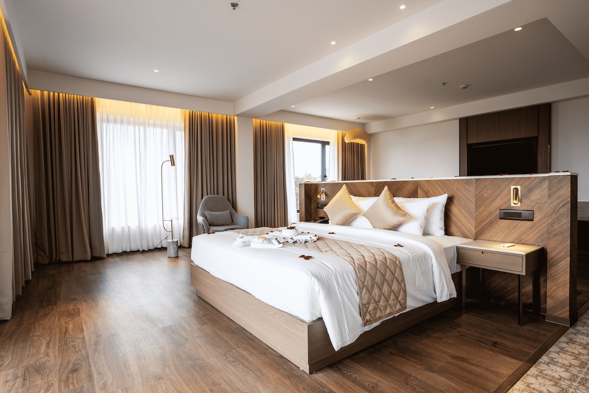 A modern hotel room with a large bed, a desk, and a chair.