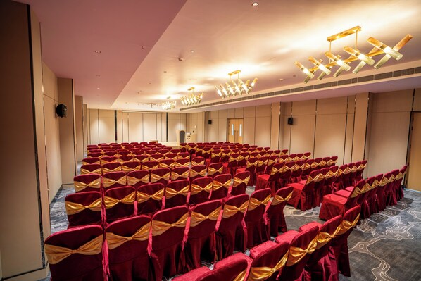 A conference room with rows of chairs, a stage, and a door. - Travancore Palace, Cochin (Aluva)