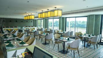 A restaurant with a high ceiling, large windows, and a variety of seating arrangements including tables and chairs.