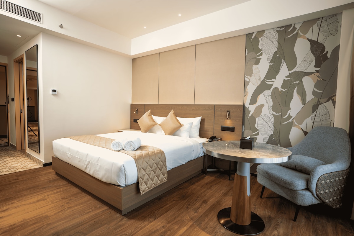 A modern hotel room with a bed, a round table, and a chair.