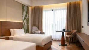 A hotel room with two beds, a seating area, and a large window with curtains. - Travancore Palace, Cochin (Aluva)