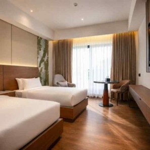 A hotel room with two beds, a seating area, and a large window with curtains. - Travancore Palace, Cochin (Aluva)
