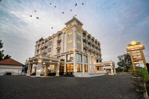A grand hotel with a prominent entrance, multiple floors, and a sign indicating amenities like a banquet hall, deluxe rooms, and a restaurant. - Travancore Palace, Cochin (Aluva)