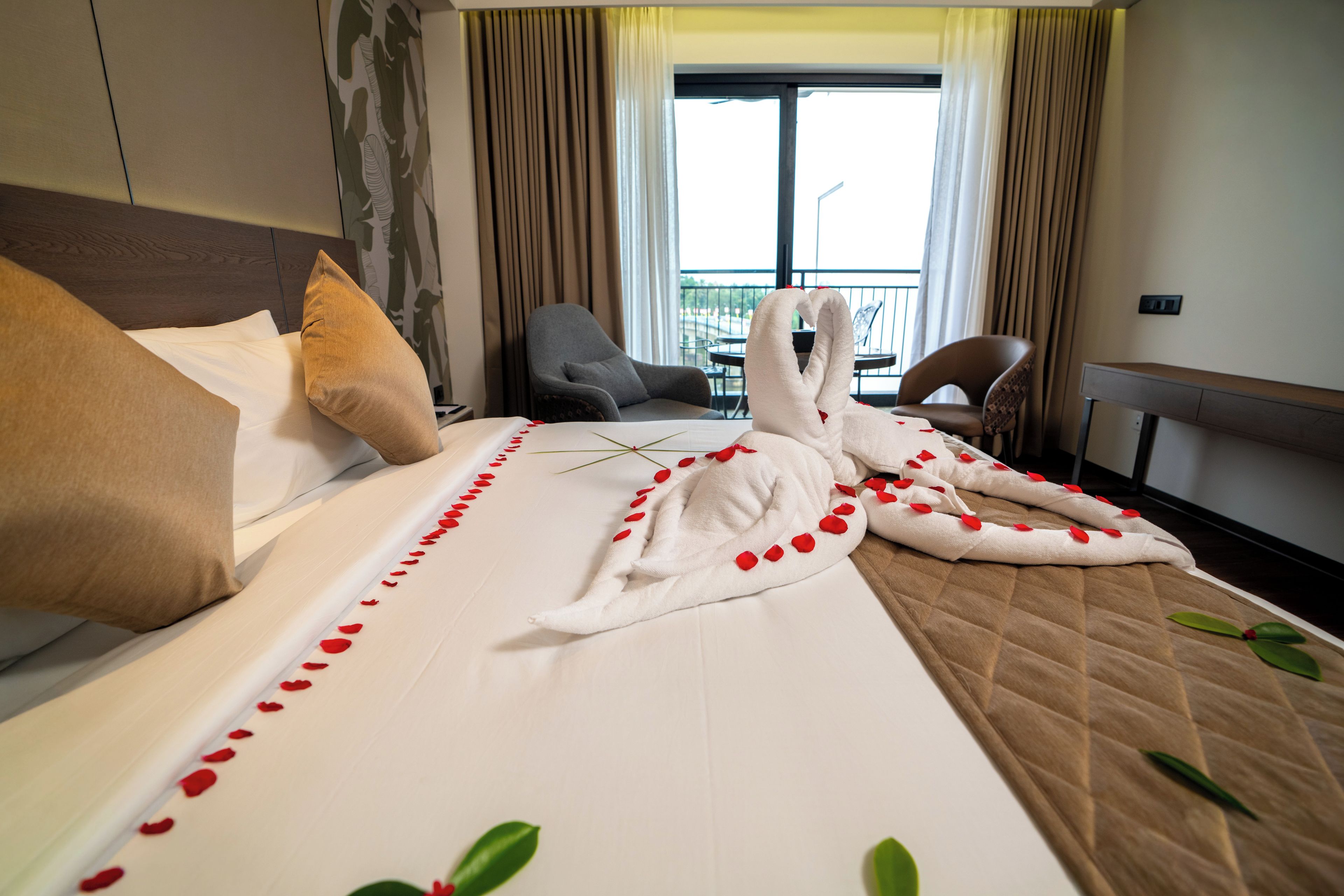 Habitación de hotel con cama, almohadas, una silla y vistas al exterior.