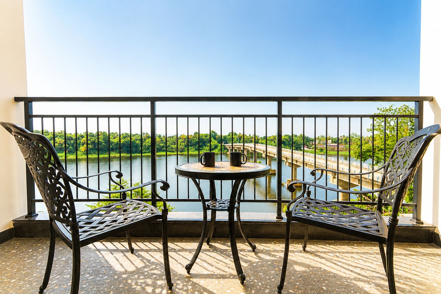 Een balkon met een tafel en twee stoelen, met uitzicht op een rivier en een brug.