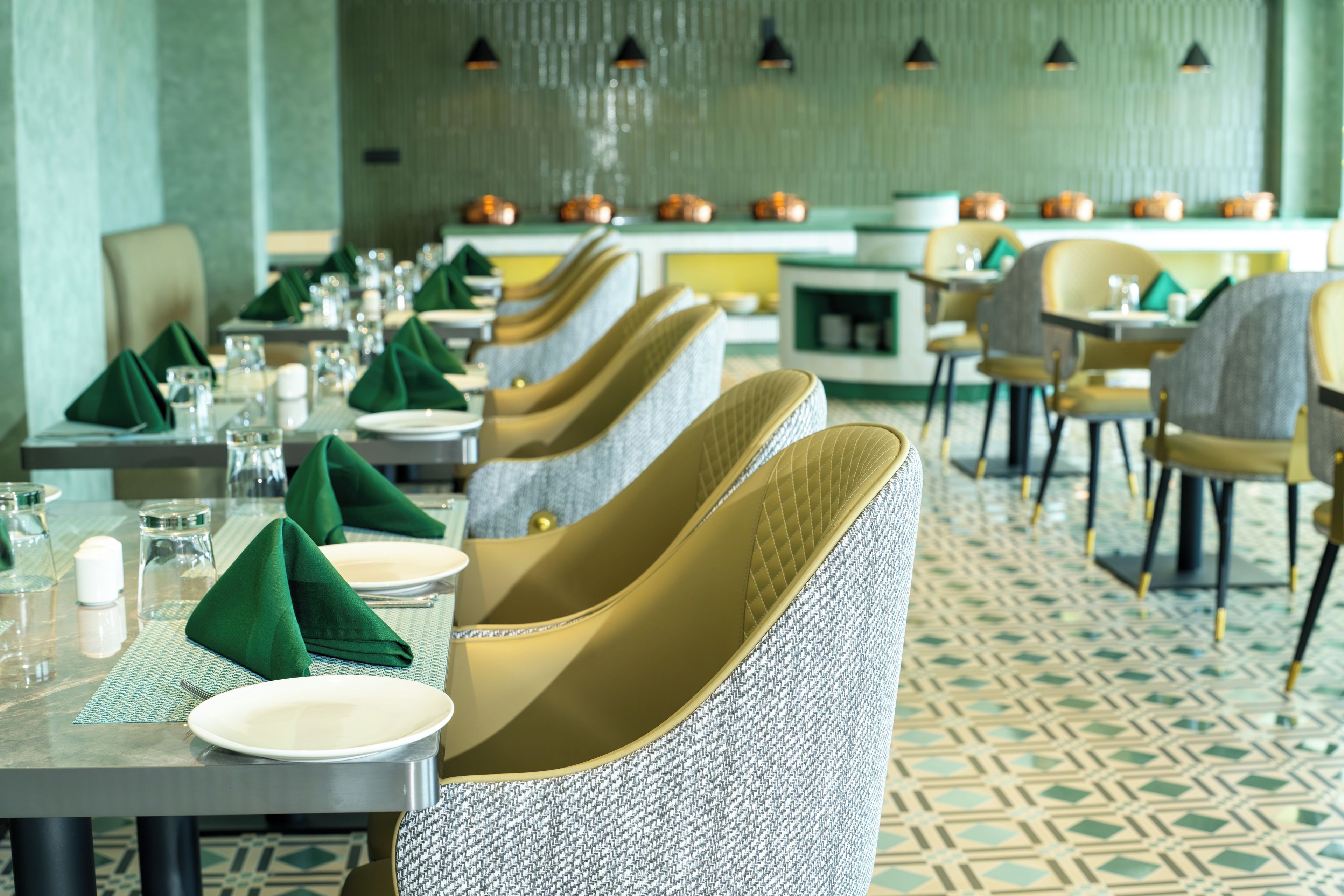 Un restaurante con una mesa larga dispuesta para comer, sillas con asientos acolchados y un suelo estampado.