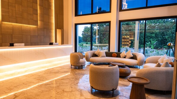 Un vestíbulo moderno con mostrador de recepción, zona de estar y grandes ventanales con vistas al exterior.