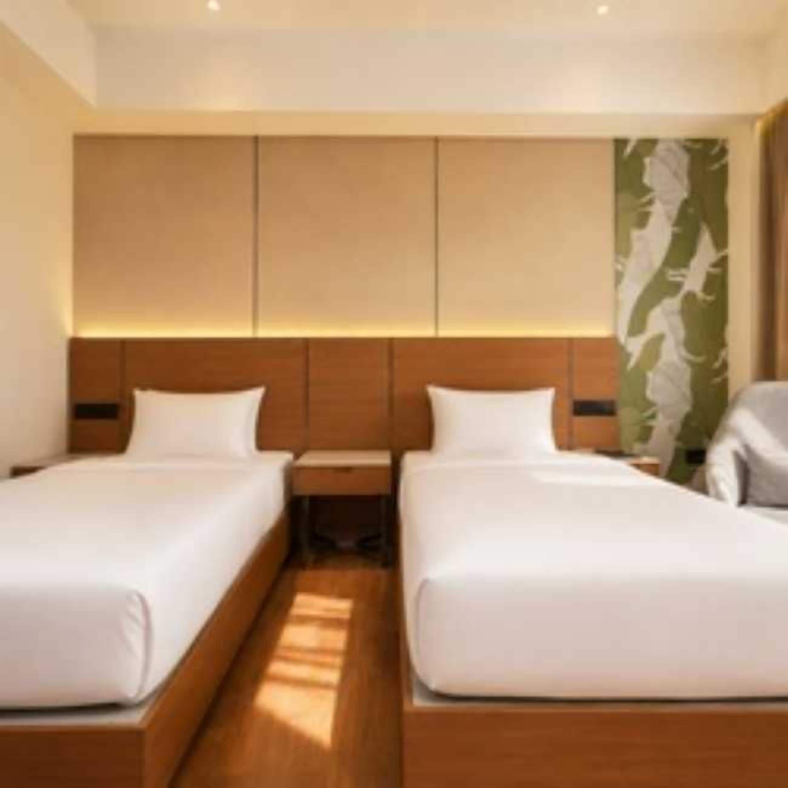 Une chambre d’hôtel avec deux lits, des têtes de lit en bois et une grande fenêtre donnant sur un beau paysage.