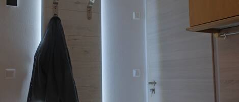 A room with a wooden door, a coat hanging on a hook, and a black countertop.