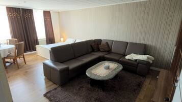 Een moderne woonkamer met een hoekbank, een salontafel en een vloerkleed.