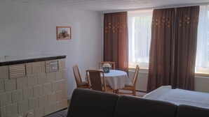 Une chambre d’hôtel comprenant un lit, un canapé, une table à manger avec des chaises, un petit coin cuisine et une fenêtre avec des rideaux.