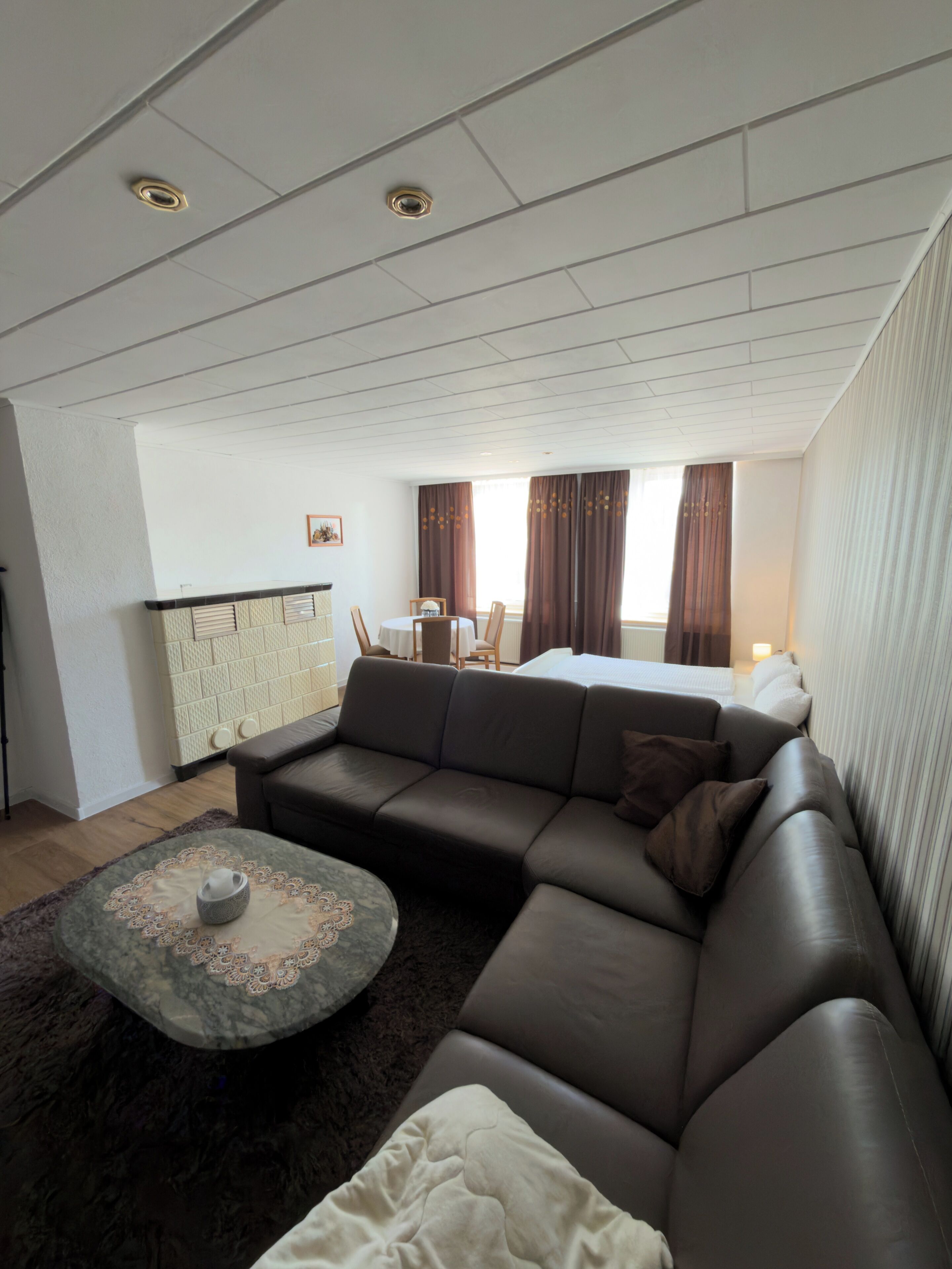 Una sala moderna con un sofá modular, una pequeña mesa redonda y un comedor con mesa y sillas.