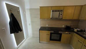 Une cuisine compacte avec des meubles en bois, un four encastré et un four à micro-ondes.