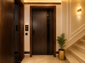 A hotel entrance with a dark wooden door, a potted plant, and a staircase. - The Queens Head - City Centre (New Delhi)