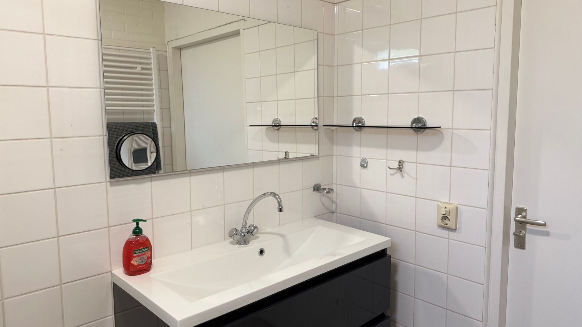 A bathroom with a white sink, a mirror, and a towel rack.