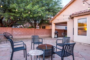 An outdoor patio with four chairs, a round table, and string lights. - Casa Christie | Charming 2BR | Firepit | Dog Friendly (Tucson)