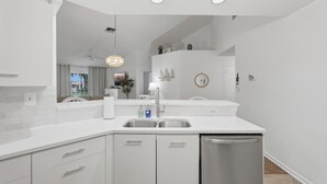 Een moderne keuken met witte kastjes, een roestvrijstalen spoelbak en een vaatwasser.