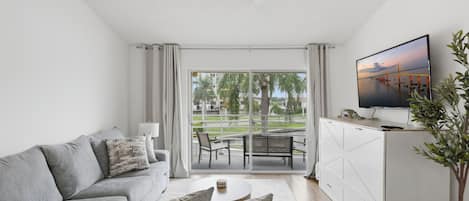 A modern living room with a sofa, coffee table, and a flat-screen TV mounted on the wall.